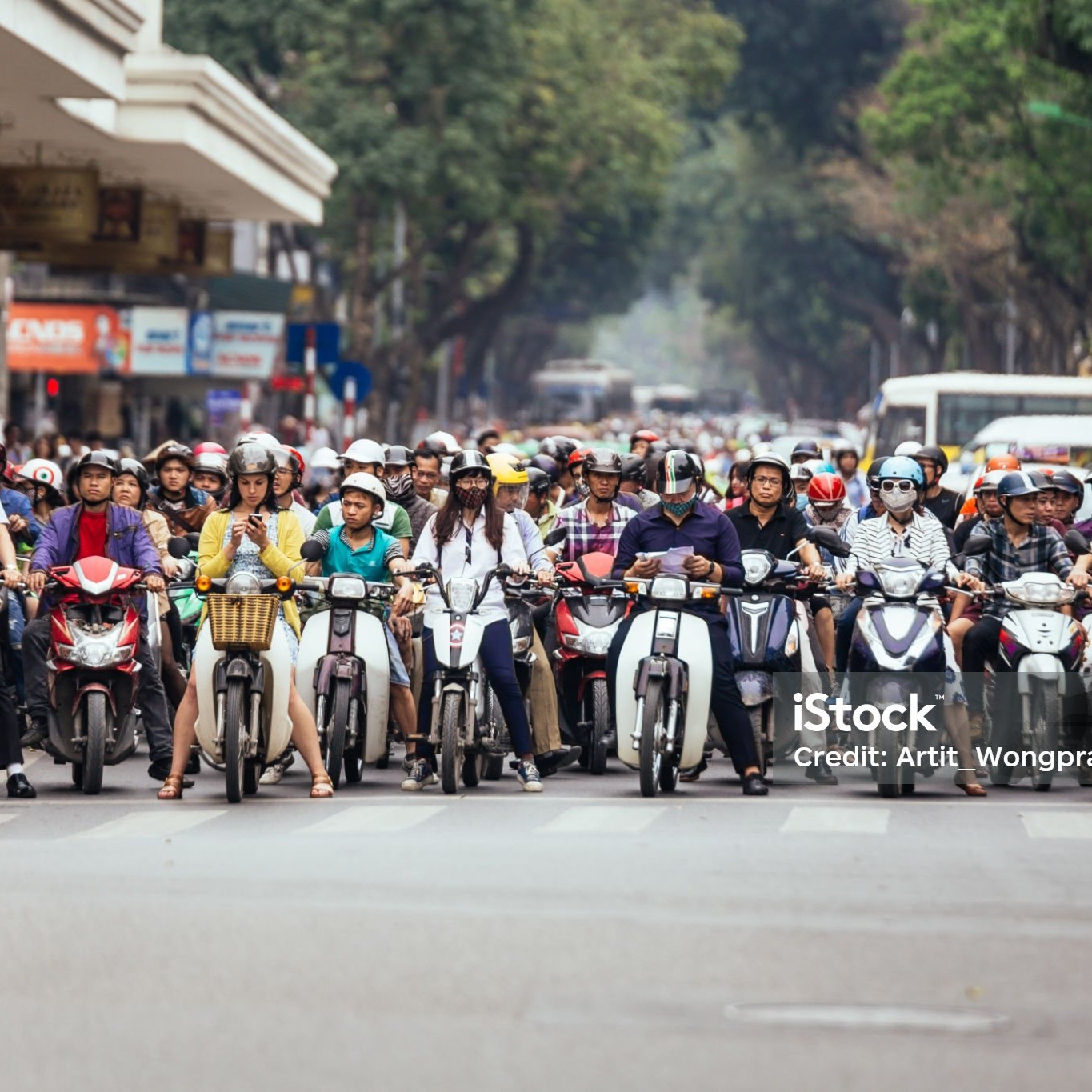 Motorcycles got traffic jam on the road with green trees in background at Hanoi, Vietnam.